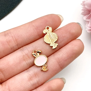 Detailed macro view of candy shaped gold charms with pink enamel and engraved texture