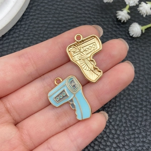 Close-up of golden and sky blue thermometer alloy pendants held by hand on black leather