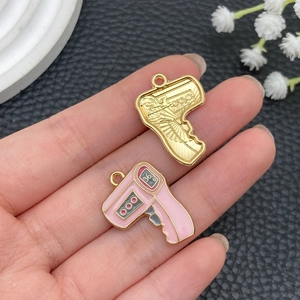 Detailed view of hand-held gold and pink enamel infrared thermometer alloy pendants
