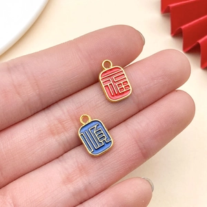 Dettaglio dei ciondoli Fu e Shun in smalto rosso e blu per la creazione di gioielli fai da te