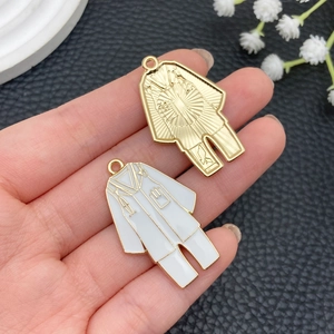 Detail of DIY alloy pendants featuring medical lab coats in gold and white enamel finish