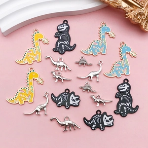 Detailopname van kleurrijke emaille dinosaurus hangers en zilveren charms voor DIY-sieraden