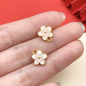 Detail showing two cherry blossom enamel charms in pink and white with gold metal plating