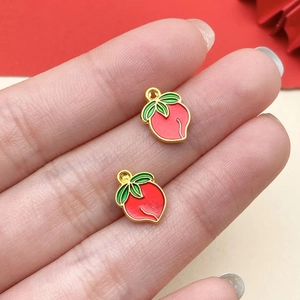 Macro view of peach enamel charms held on fingertips for DIY jewelry size scale