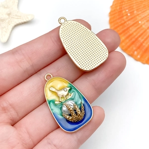 Détail d'un pendentif océan coloré avec finition émail et perle d'imitation