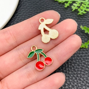 Macro shot of cherry charms with gold brushed metal and red enamel drips for DIY jewelry