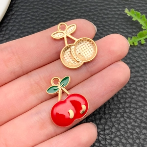 Macro view of cherry-shaped enamel pendants with gold finish for DIY jewelry making