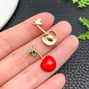 Macro detail of red cherry enamel charms with golden metal back for DIY jewelry making