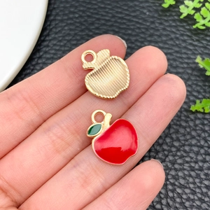 Close-up of apple alloy pendants with red enamel and gold stripes for DIY jewelry making