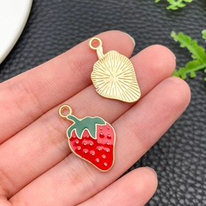 Close-up of strawberry enamel charms showing red drip oil finish and gold metal back