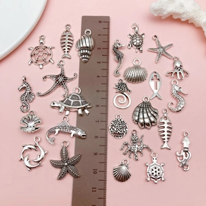 Flat lay of antique silver ocean animal charms with a ruler for size measurement
