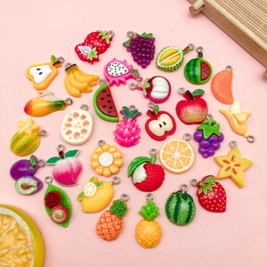 Vue détaillée de pendentifs de fruits en résine avec anneaux métalliques pour création DIY
