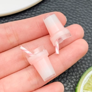 Makroaufnahme von Miniatur-Milchshake-Bechern in Rosa mit gestreiften Strohhalmen für DIY