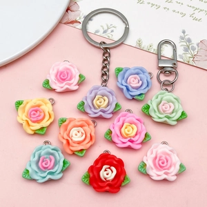 Resin camellia flower pendants with green leaves and metal clasps in multiple colors