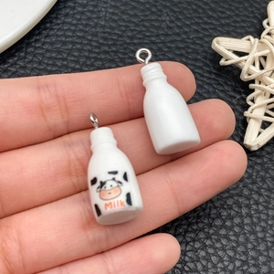 Close-up of DIY resin miniature milk bottle charms held in hand for jewelry making