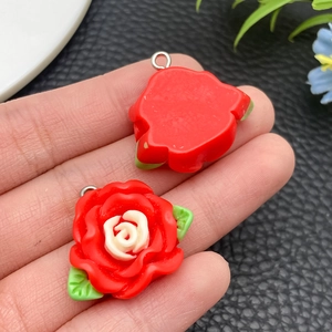 Detail of resin camellia flower pendant with green leaves and metal loop for DIY crafts