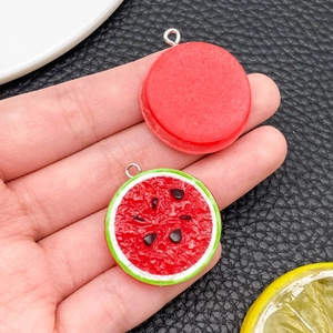 Macro shot of resin watermelon slice pendant and red disc with silver hooks for DIY jewelry