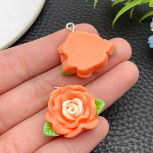 Detailed macro view of resin camellia flower pendant with green leaves and silver metal ring