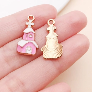 Dettaglio di ciondoli a forma di chiesa in smalto rosa e bianco con finitura dorata DIY