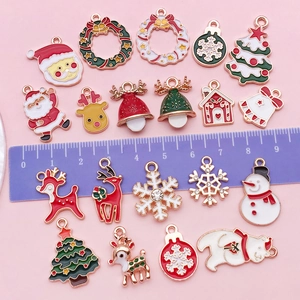 Détail macro de breloques de Noël émaillées avec règle montrant les tailles de 1cm à 3cm