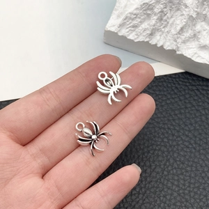 Close-up of silver spider charms with vintage finish and hanging loops for DIY jewelry