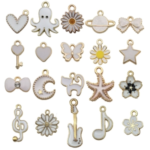 White enamel and gold-plated alloy charms in shapes of butterfly, moon, and starfish