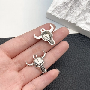 Macro view of vintage silver bull skull pendants for DIY jewelry making on leather background