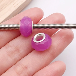 Detalle macro de cuentas de resina violeta facetadas con núcleo de metal en cadena
