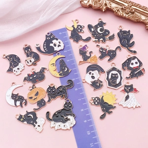 Detailed view of Halloween cat charms with size ruler on a decorative pink background