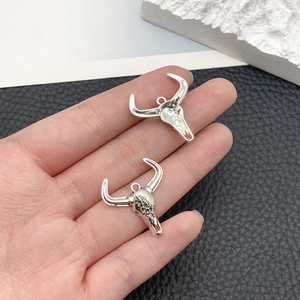 Detailed view of silver bull skull pendant with vintage floral carvings and small size