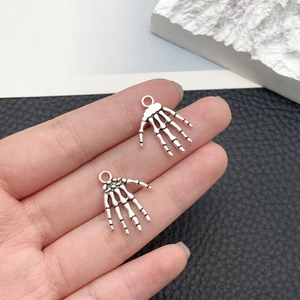 Detail of silver alloy skeleton hand pendants for DIY jewelry with vintage finish