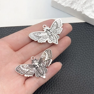 Close-up of vintage silver alloy butterfly and skull moth pendants for DIY jewelry