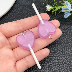 Vista dettagliata di ciondoli a lecca-lecca a cuore in resina viola con glitter per fai-da-te