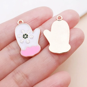 Detail of pink and white Christmas glove charms with snowflake patterns for DIY bracelets