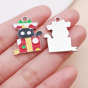 Detalle del colgante de gato navideño con caja roja y reverso plateado texturizado