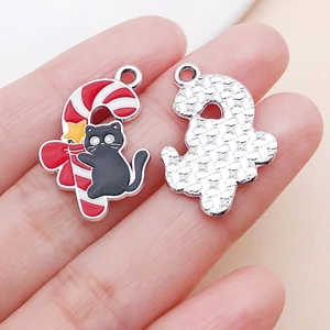 Detalle de colgantes de gato esmaltados con bastones de caramelo y reverso de metal plateado