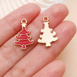 Detalle macro de dijes de árbol de Navidad en esmalte rojo mostrando frente y reverso dorado