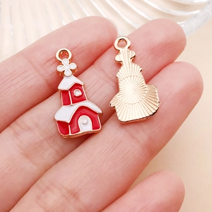 Vista macro de un colgante de casa navideña de esmalte rojo y blanco para joyas DIY