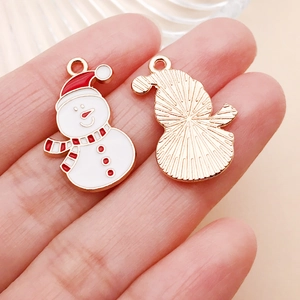 Detalle del colgante de muñeco de nieve de esmalte rojo y blanco para joyas DIY con fondo dorado