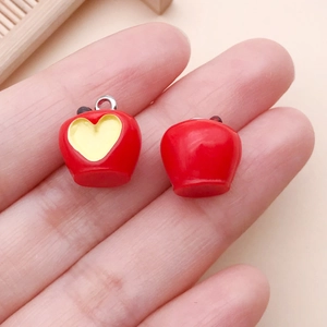 Dettaglio dei ciondoli a forma di mela in resina con cuore giallo per gioielli DIY