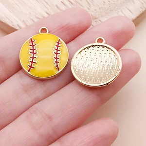 Makroaufnahme von gelben Emaille-Baseball-Anhängern mit roten Nähten und goldener Rückseite