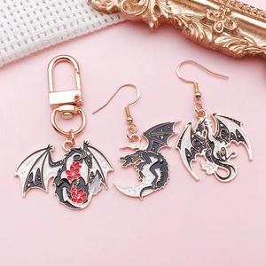 Dark fantasy dragon and moon alloy jewelry set with rose gold hooks on pink background