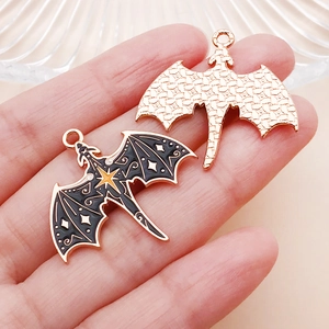 Detailed view of gothic dragon moon bat charms with black gold stars and textured gold back