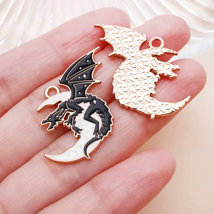 Close-up of gothic dragon and crescent moon charms with black and white enamel details