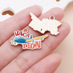 Gros plan d'un pendentif avion bleu avec lettrage Vacation et dos doré texturé