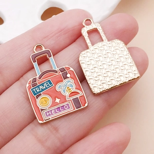 Vue macro de breloques valise de voyage en émail rose pour la création DIY