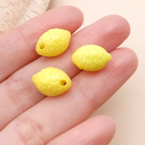 Vista macro de tres dijes de limón en acrílico amarillo con agujeros para crear joyas DIY