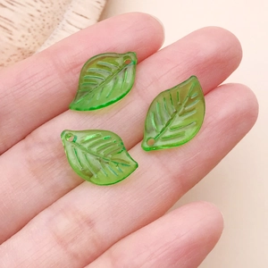 Detalle de colgantes de hojas de acrílico verde translúcido en la mano para comparar