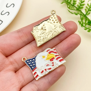 Detail of USA eagle flag pendants for DIY jewelry making held in hand for scale