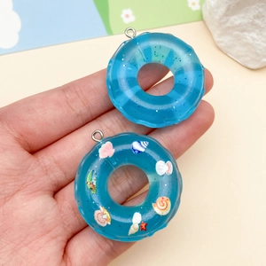 Dettaglio di ciondoli a ciambella in resina blu con glitter e conchiglie per gioielli DIY